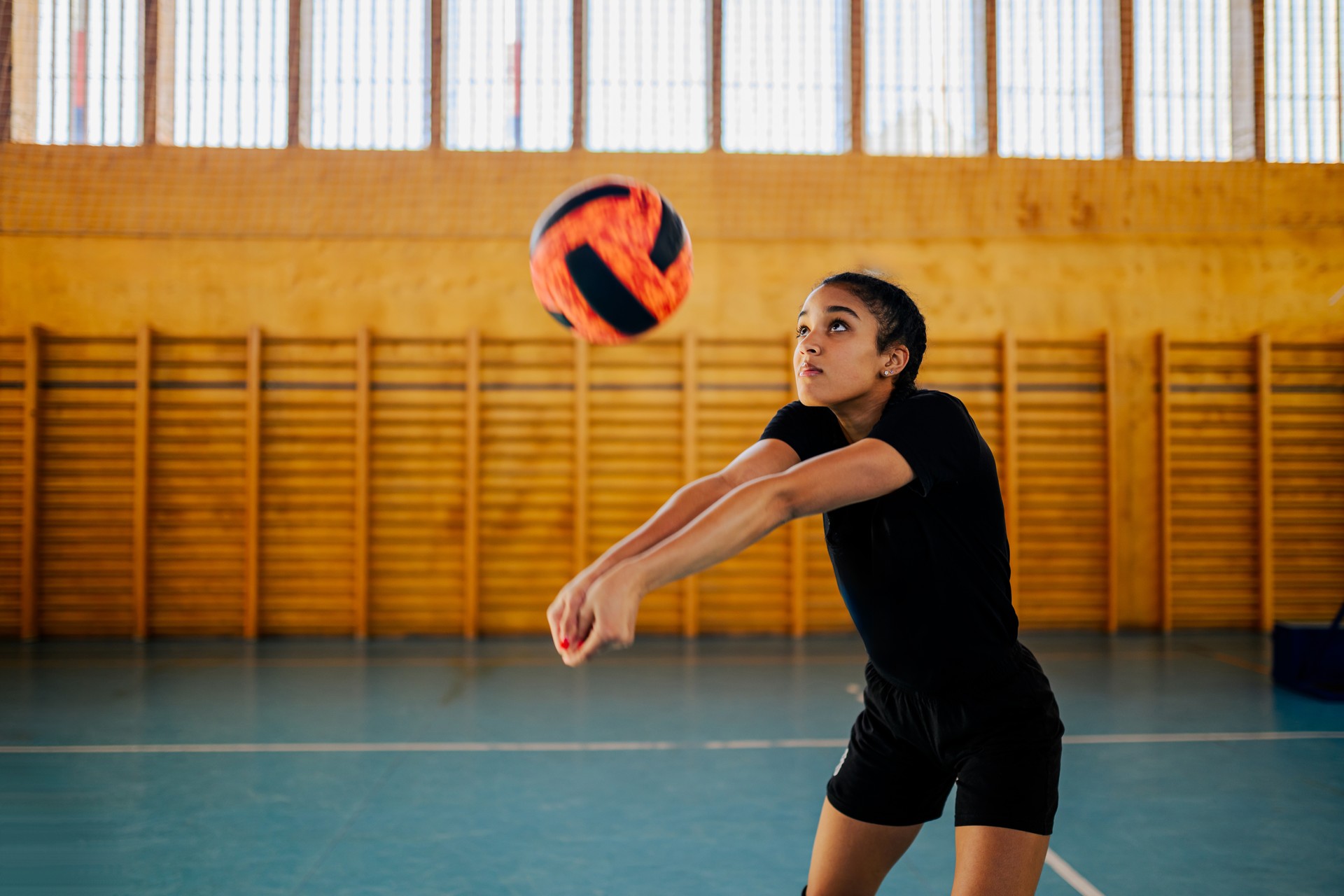 A multicultural teenage volleyball player passing a ball on court.