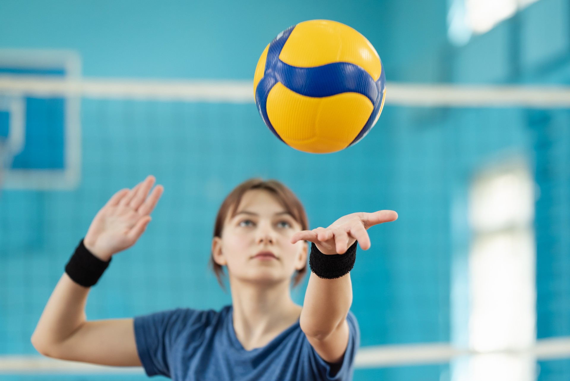 Photo in action of a young girl serving the ball